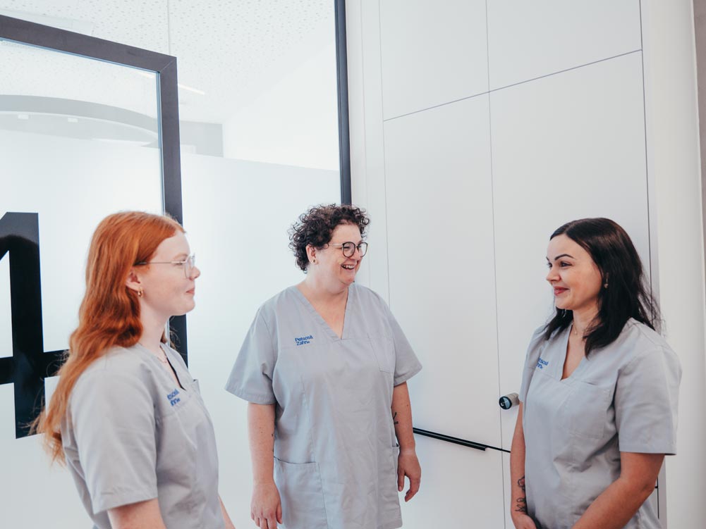 Drei Mitarbeitende der Praxis Petsos&Zahn in Soest unterhalten sich und lachend aber